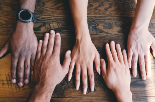 five human hands on brown surface