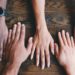five human hands on brown surface