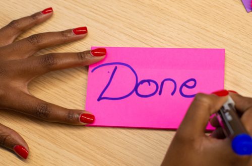 person with red manicure holding purple paper